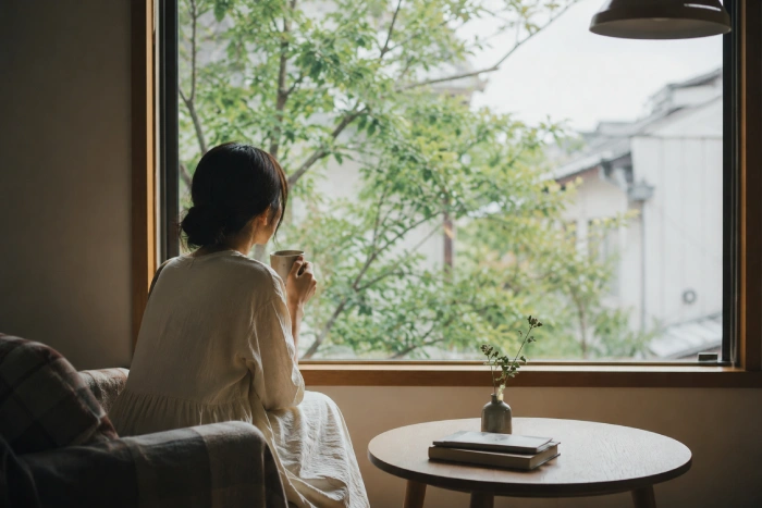 静かな部屋で窓の外を眺めながら穏やかな時間を過ごす人物の日常風景