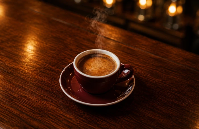 湯気が立つホットコーヒーが木製カウンターに置かれた落ち着いた喫茶空間