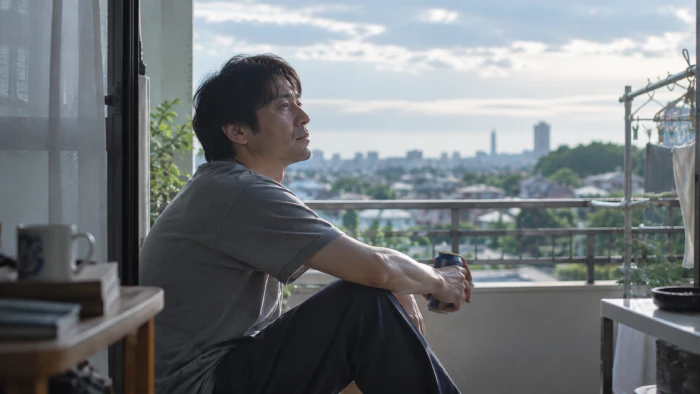 ベランダで街を眺めながら物思いにふける中年男性、穏やかな昼下がりの風景