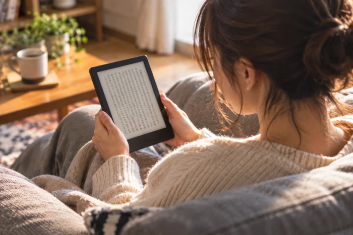 ソファで電子書籍を読む女性と手元の電子書籍リーダー