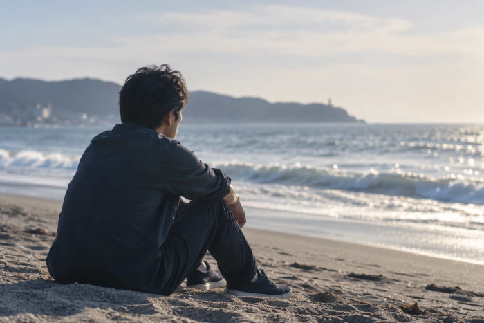 海辺で一人静かに海を見つめる男性